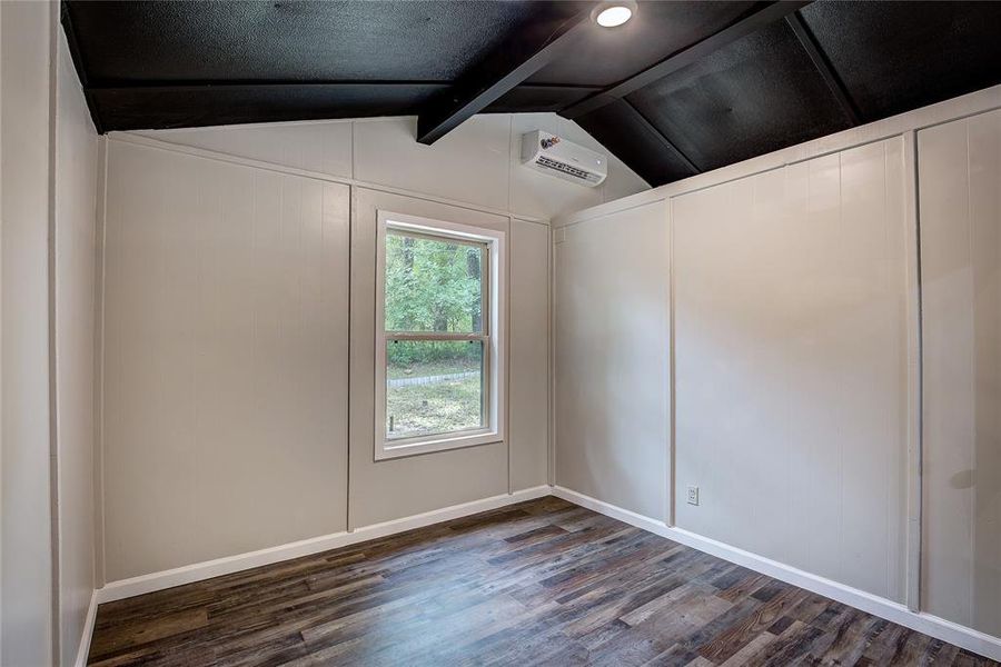 Empty room with dark wood-type flooring and lofted ceiling with beams