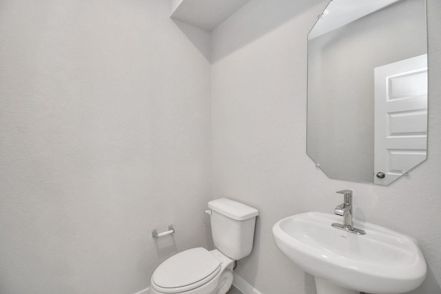 This half bathroom features a stylish pedestal sink, modern hardware, and bright recessed lighting, creating a sleek and inviting space. Sample photo of completed home with similar floor plan. Actual colors and selections may vary. This half bathroom features a stylish pedestal sink, modern hardware, and bright recessed lighting, creating a sleek and inviting space. Sample photo of completed home with similar floor plan. Actual colors and selections may vary.