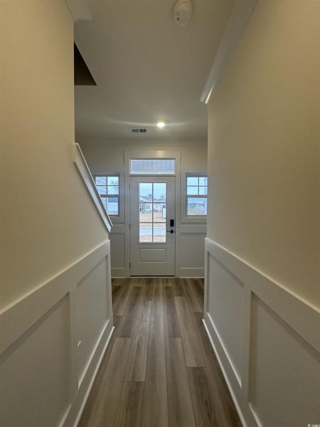 Doorway to outside featuring a decorative wall, a wainscoted wall, and wood finished floors