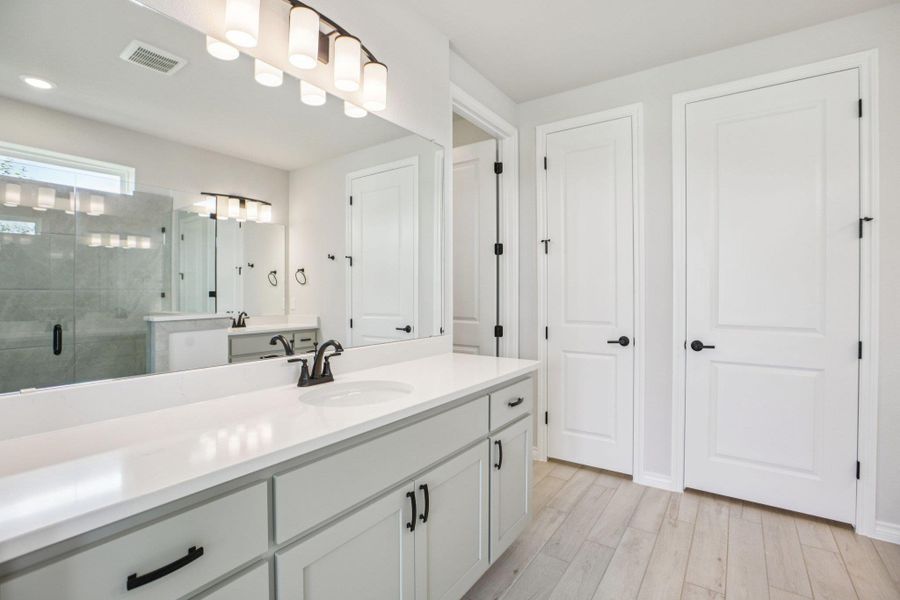 Bathroom featuring a shower stall, vanity, and light wood-type flooring