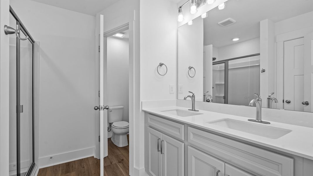 Highly functional and elegant en-suite with dual vanities, tiled walk-in shower, and refined finishes