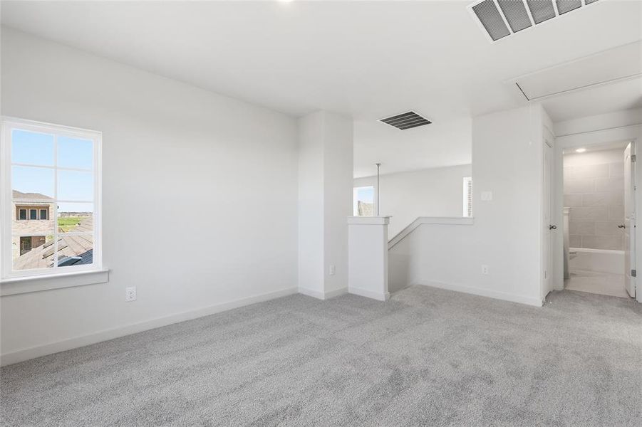 Carpeted secondary living space featuring a window with exterior views, white trim, and a partial wall overlooking a lower level