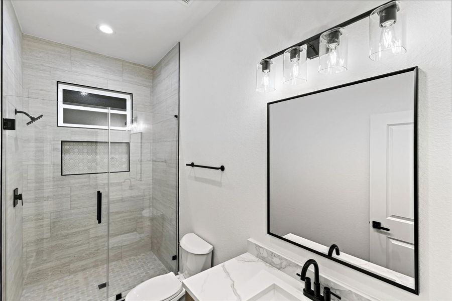 This modern bathroom features a glass-enclosed shower with sleek tilework, a large mirror, and contemporary lighting. The black fixtures and marble countertop add a touch of elegance, while the neutral color palette provides a clean, sophisticated look. This modern bathroom features a glass-enclosed shower with sleek tilework, a large mirror, and contemporary lighting. The black fixtures and marble countertop add a touch of elegance, while the neutral color palette provides a clean, sophisticated look.