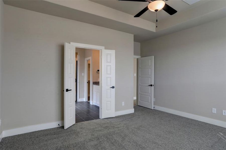 Unfurnished bedroom with dark carpet and a raised ceiling