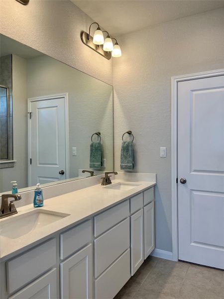 Full bathroom with double vanity and light tile patterned floors