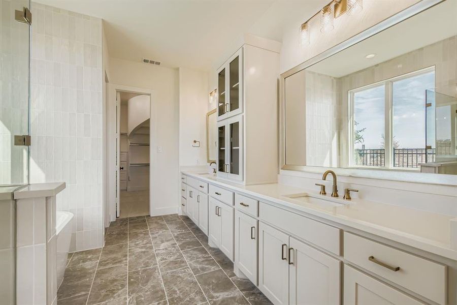 Bathroom featuring double vanity, a spacious closet, a tub to relax in, and a shower with shower door