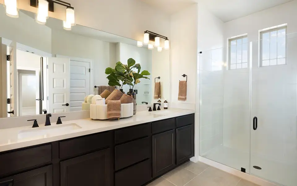 Bathroom featuring double vanity, a shower stall, and light tile patterned flooring Bathroom featuring double vanity, a shower stall, and light tile patterned flooring