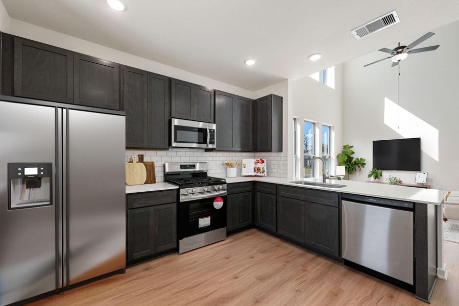 This modern chef's kitchen blends functionality with contemporary style, featuring sleek dark gray shaker-style cabinetry paired with white quartz countertops, classic white subway tile backsplash, recessed lighting, and stainless steel appliances. *Virtually Staged This modern chef's kitchen blends functionality with contemporary style, featuring sleek dark gray shaker-style cabinetry paired with white quartz countertops, classic white subway tile backsplash, recessed lighting, and stainless steel appliances. *Virtually Staged