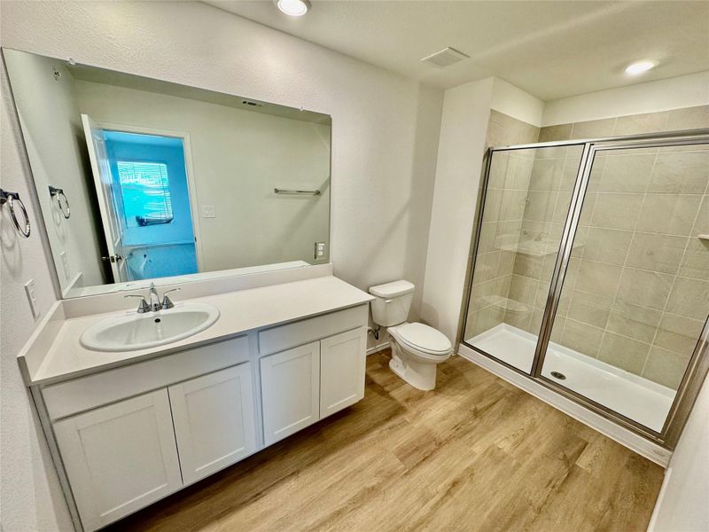 Full bath with vanity, a stall shower, light wood finished floors, and recessed lighting Full bath with vanity, a stall shower, light wood finished floors, and recessed lighting