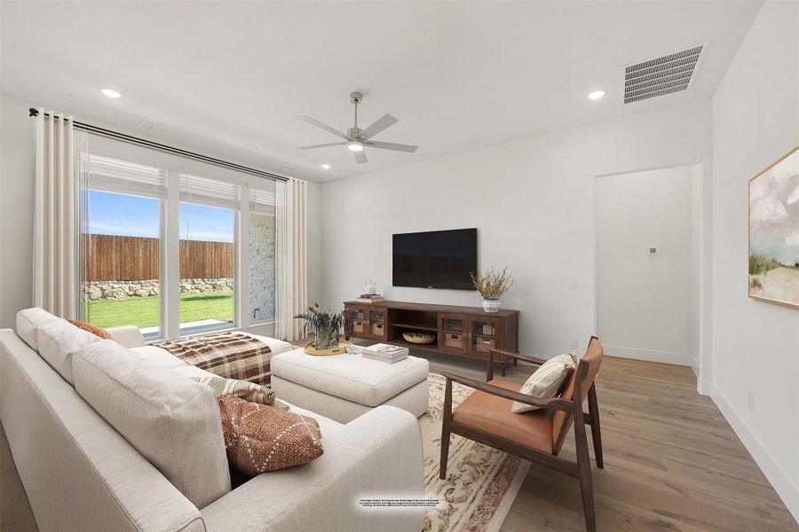 Living room with sectional sofa, ceiling fan, wall-mounted TV, and sliding glass door to backyard Living room with sectional sofa, ceiling fan, wall-mounted TV, and sliding glass door to backyard