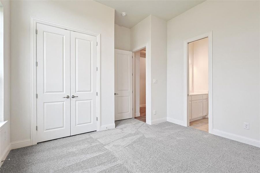 Unfurnished bedroom with connected bathroom, light carpet, and a closet