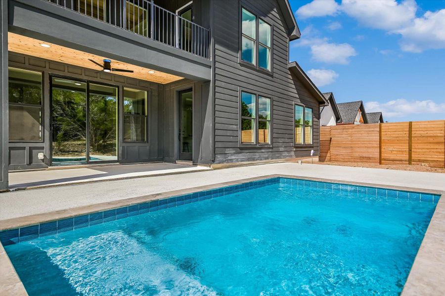 A private pool with sleek concrete decking abuts a modern dwelling with a second-story balcony.