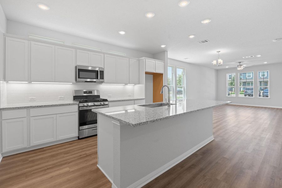 Kitchen featuring stainless steel appliances, light wood-type flooring, recessed lighting, white cabinetry, and tasteful backsplash