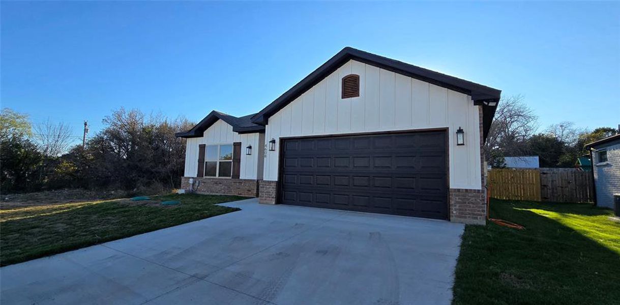 Modern inspired farmhouse featuring board and batten siding, concrete driveway, brick siding, and an attached garage