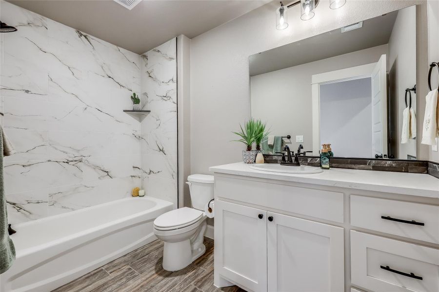 Bathroom with vanity, bathtub / shower combination, and wood finish floors Bathroom with vanity, bathtub / shower combination, and wood finish floors