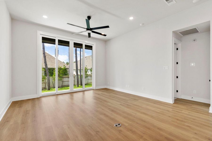 Sunlit living room with wide-plank flooring, recessed lighting, and oversized sliding doors to the backyard.