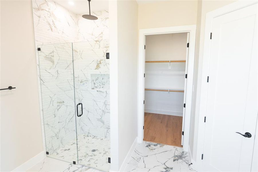 Full bathroom with light marble finish floors, a marble finish shower, and a spacious closet
