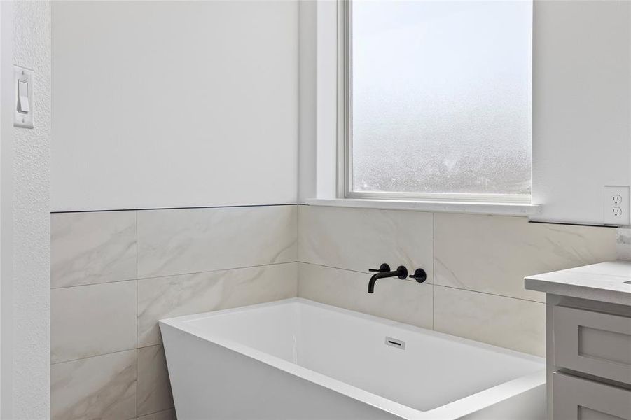 Bathroom with a bath, tile walls, and vanity