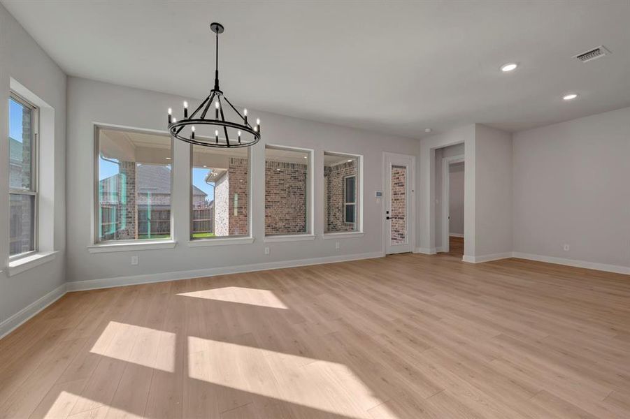 Unfurnished dining area with hanging lights and light wood-style floors