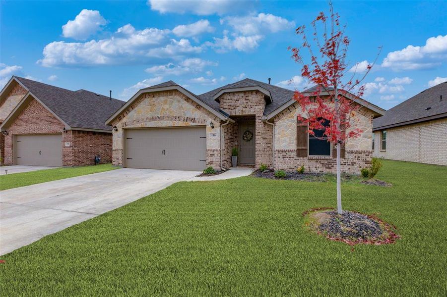 View of front of property featuring a front lawn and a garage