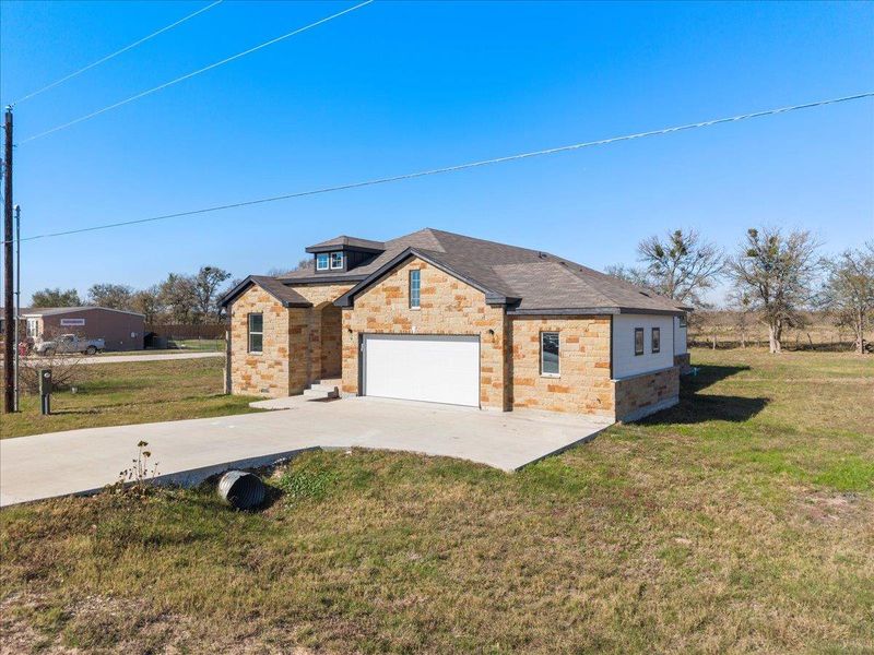 View of front facade with driveway, a front yard, a garage, and stone siding View of front facade with driveway, a front yard, a garage, and stone siding