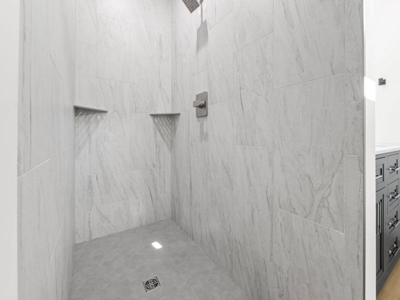 Walk-in shower with large-format wall tiling and hexagonal floor tiling