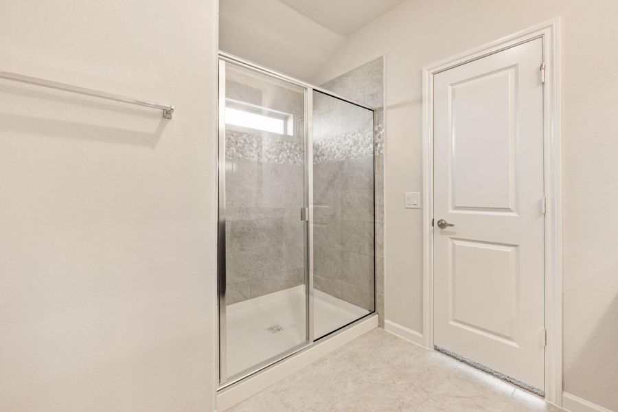 Walk-in shower with glass sliding doors, gray tile walls, and small window above