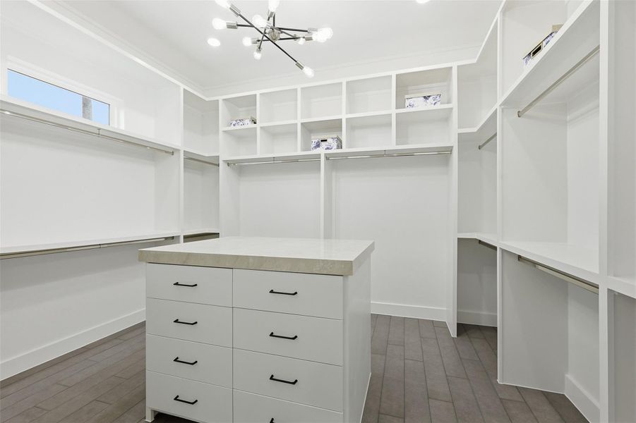 An 11x13 walk-in closet designed to impress, featuring a porcelain-topped island, abundant drawer storage, and generous hanging space throughout.
