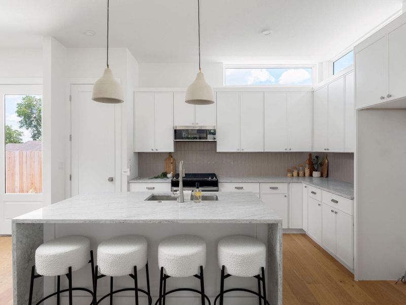 White cabinetry and natural wood floors complete this well-appointed kitchen with an elegant island.