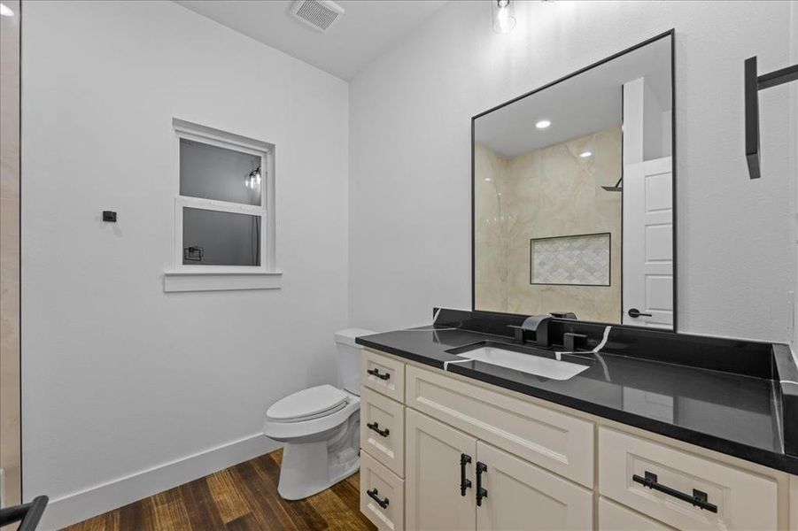 Full bath featuring vanity with dark counters, , wood-style floors, and a marble-like finished shower Full bath featuring vanity with dark counters, , wood-style floors, and a marble-like finished shower