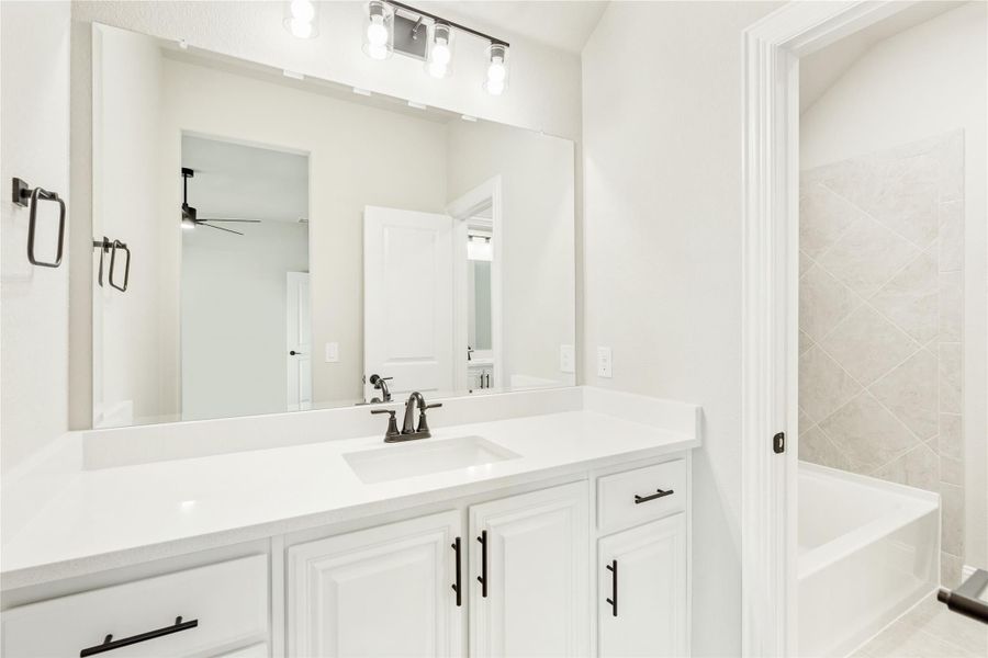Bathroom with white vanity, single sink, large mirror, and tiled soaking tub Bathroom with white vanity, single sink, large mirror, and tiled soaking tub