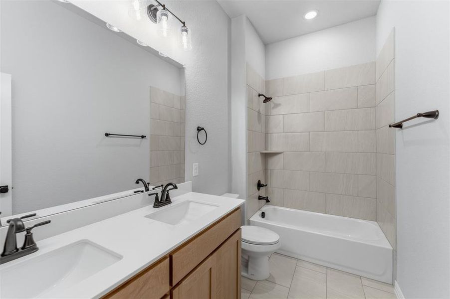 Bathroom with double vanity, shower / washtub combination, light tile patterned floors, and recessed lighting