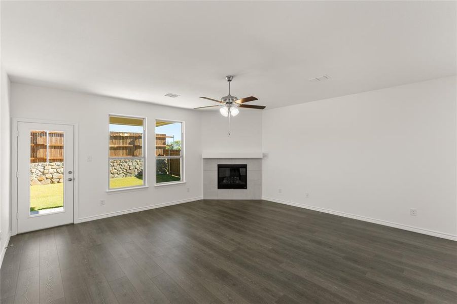 Unfurnished living room featuring a tile fireplace, dark hardwood / wood-style floors, and ceiling fan