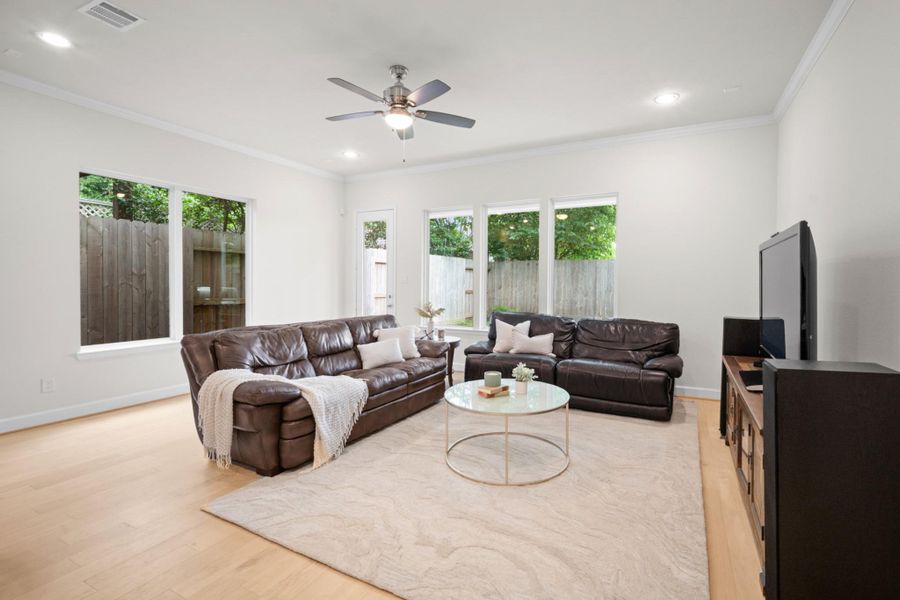 Generous family room with crown molding, engineered wood floors, ceiling fan, and windows on three sides — bright without trying, comfortable without effort. Generous family room with crown molding, engineered wood floors, ceiling fan, and windows on three sides — bright without trying, comfortable without effort.