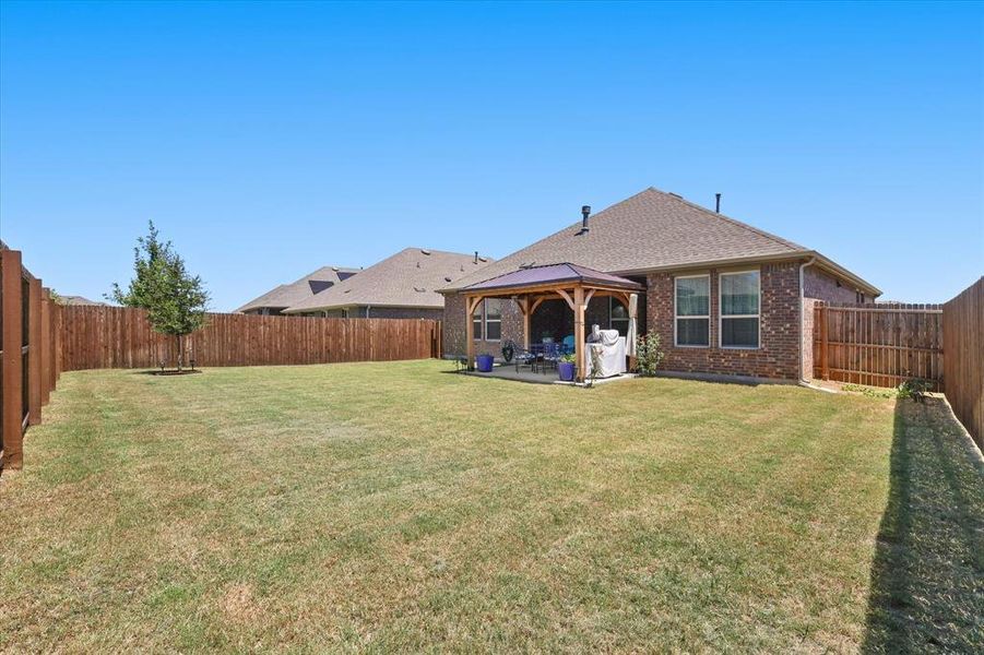 Rear view of house featuring a gazebo, brick siding, a shingled roof, a patio, and a fenced backyard Rear view of house featuring a gazebo, brick siding, a shingled roof, a patio, and a fenced backyard
