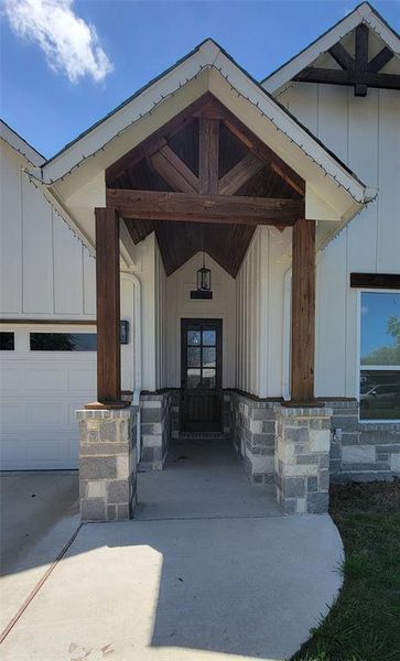 Entrance to property featuring covered porch, board and batten siding, and driveway