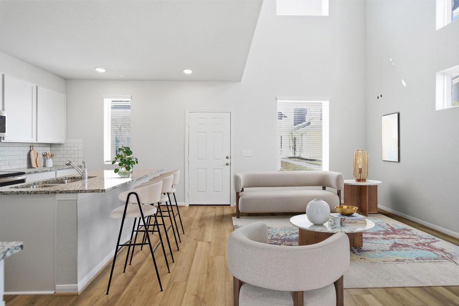 Living area with light wood-style floors, healthy amount of natural light, and a high ceiling