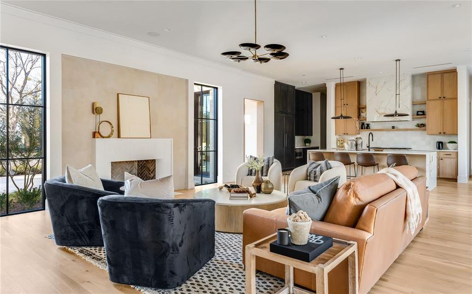 Living room with crown molding, a high end fireplace, sink, and light hardwood / wood-style flooring