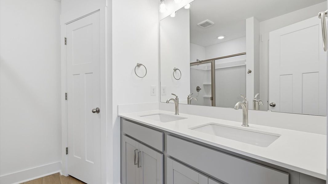 Notable primary bath featuring dual vanity, walk-in shower, and tasteful design touches throughout at Saluda Crossing