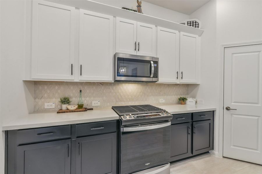 A gas range and microwave complement this generously sized kitchen, while a walk-in pantry keeps essentials close at hand! The stunning diamond shaped tile backsplash adds beauty and warmth to the space.