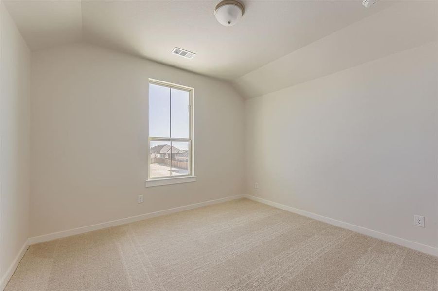 Unfurnished room featuring lofted ceiling and light carpet