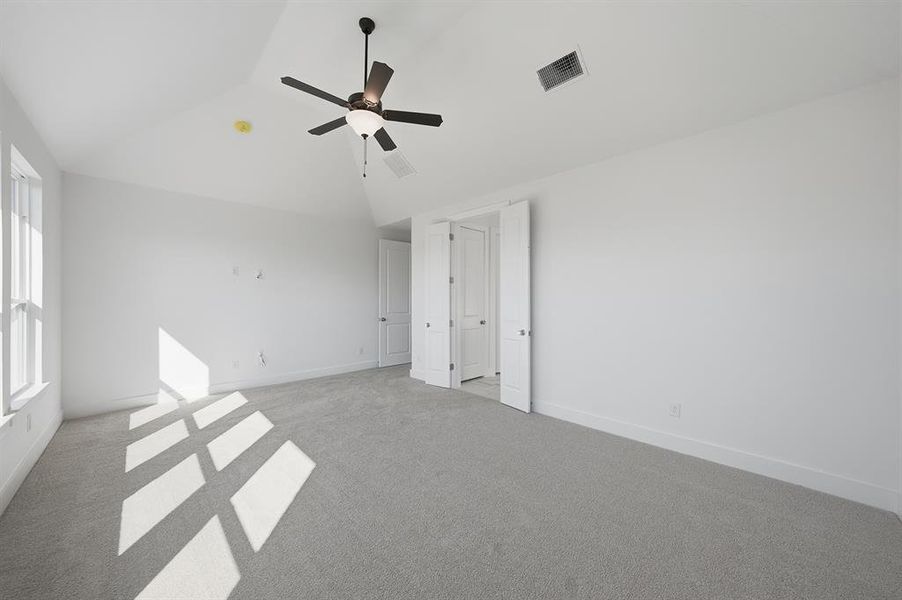 Unfurnished bedroom with vaulted ceiling, ceiling fan, and carpet floors Unfurnished bedroom with vaulted ceiling, ceiling fan, and carpet floors