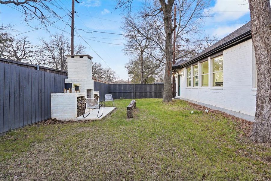 Fenced backyard with a brick fireplace and a patio