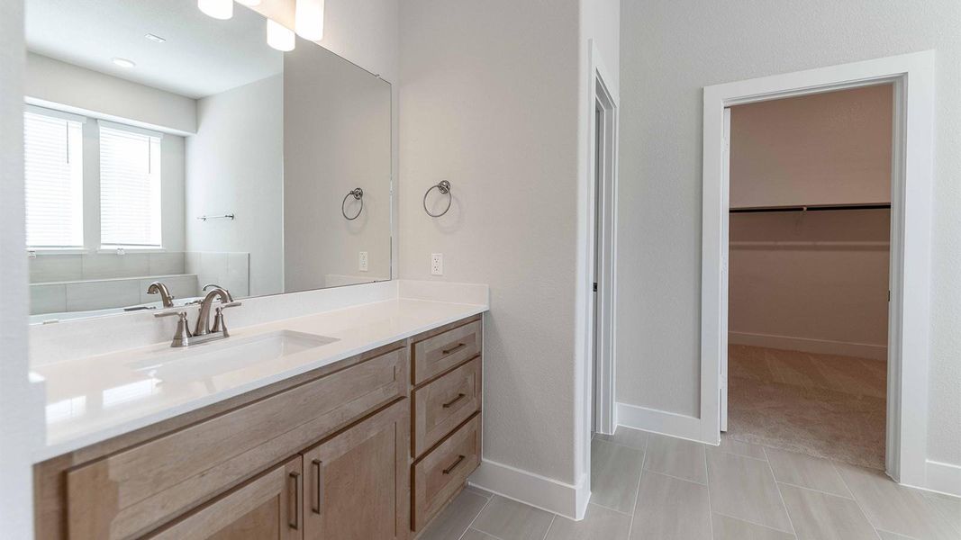 Full bathroom with vanity, a walk in closet, and light tile patterned floors Full bathroom with vanity, a walk in closet, and light tile patterned floors