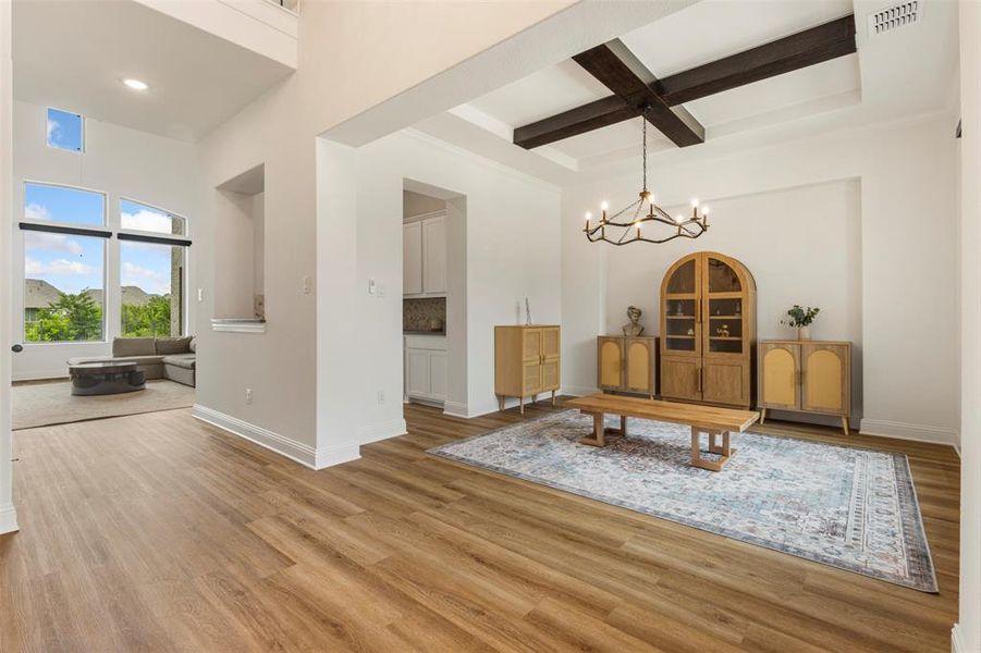 Dining room with coffered ceiling, a towering ceiling, a chandelier, light wood-type flooring, and beamed ceiling Dining room with coffered ceiling, a towering ceiling, a chandelier, light wood-type flooring, and beamed ceiling