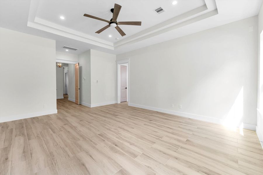 Spacious bedroom featuring elegant tile floors, a stylish accent wall, and a modern ceiling fan—perfect for creating your personal retreat.