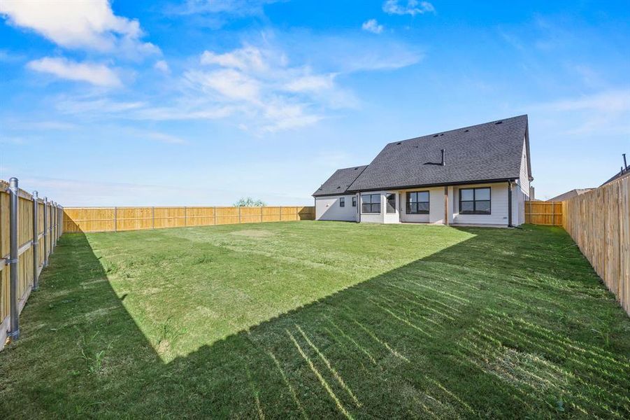 Rear view of property featuring a fenced backyard, a shingled roof, and a patio area