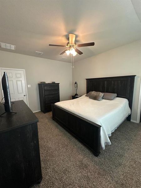 Bedroom with dark carpet and a ceiling fan