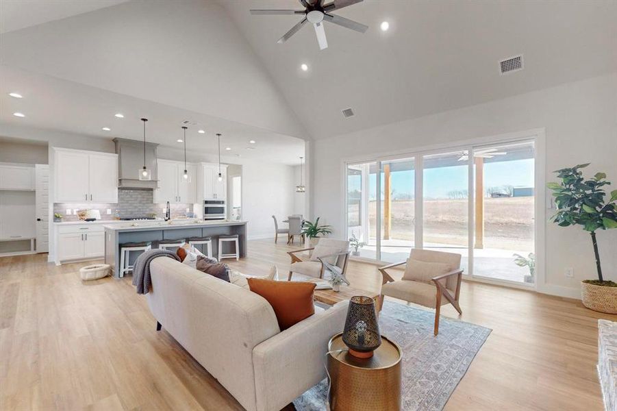 Living room with ceiling fan, sink, high vaulted ceiling, and light hardwood / wood-style floors