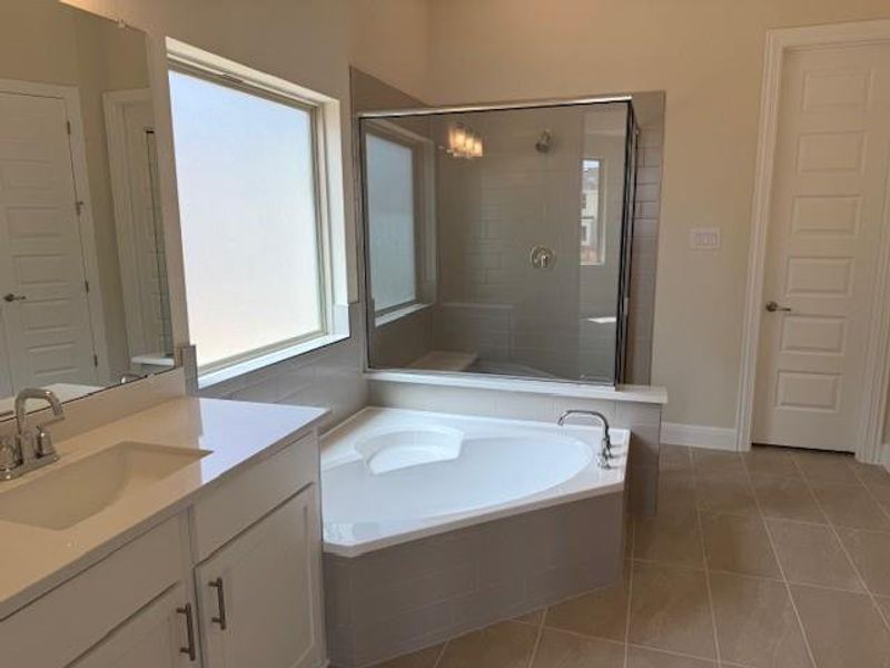 Bathroom with vanity, tile patterned flooring, a garden tub, and a tile shower Bathroom with vanity, tile patterned flooring, a garden tub, and a tile shower